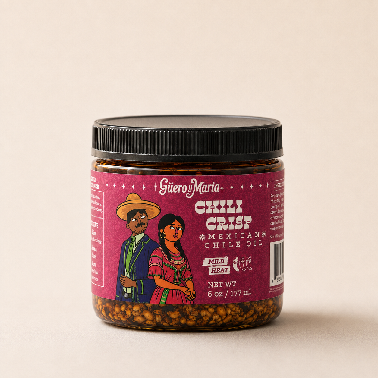 A jar of Guero y Marta Chilli Crisp Mexican Chile Oil with a black lid and a magenta label featuring an illustration of Guero y Maria, set against a plain beige background.