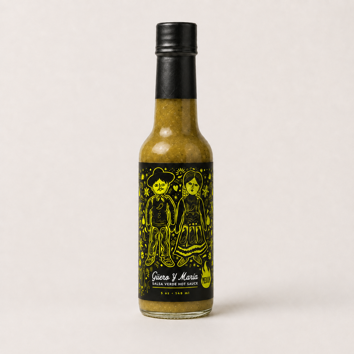 A bottle of Guasa y Maria Hot Sauce with a black cap and a black label featuring yellow illustrations of guero and Maria characters, set against a plain light background.